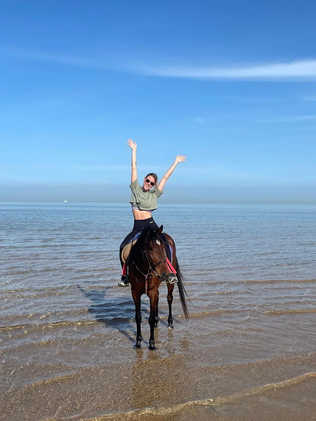 Kaina à cheval dans la mer, les bras levés vers le ciel