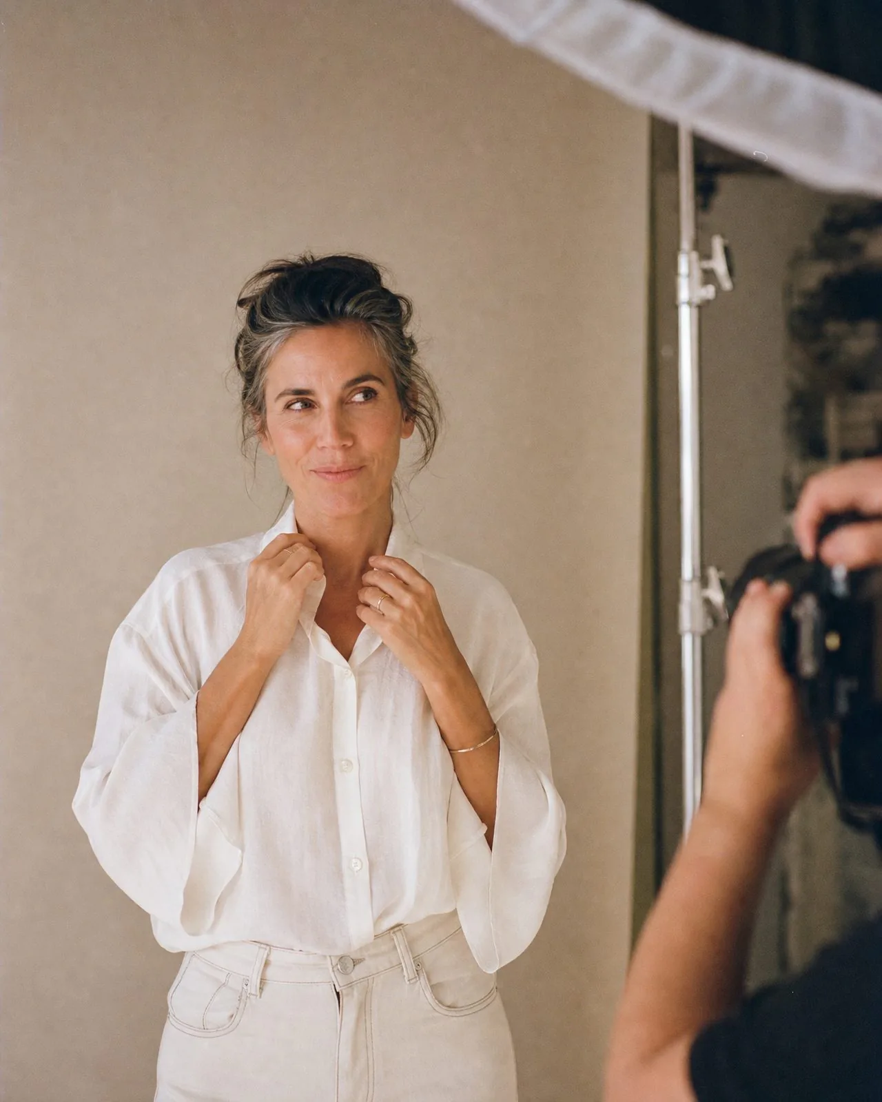 Nadia devant l'objectif, ajustant son col avec un sourire en coin